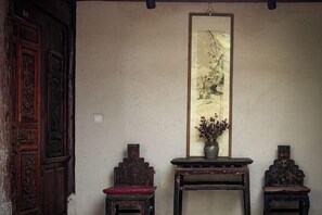 Una habitación tradicional con una puerta de madera, un cuadro enmarcado y dos mesitas con adornos decorativos.