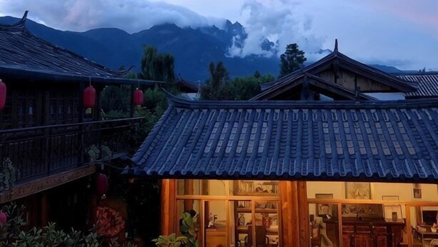 A traditional building with a tiled roof and wooden structure, surrounded by greenery. - Baisha No. 66 Post Station (Yulong)