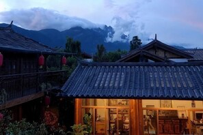 A traditional building with a tiled roof and wooden structure, surrounded by greenery. - Baisha No. 66 Post Station (Yulong)