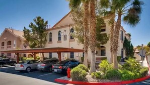 Ein Hotel mit heller Sandsteinfassade, zahlreichen Fenstern und einem überdachten Parkbereich.