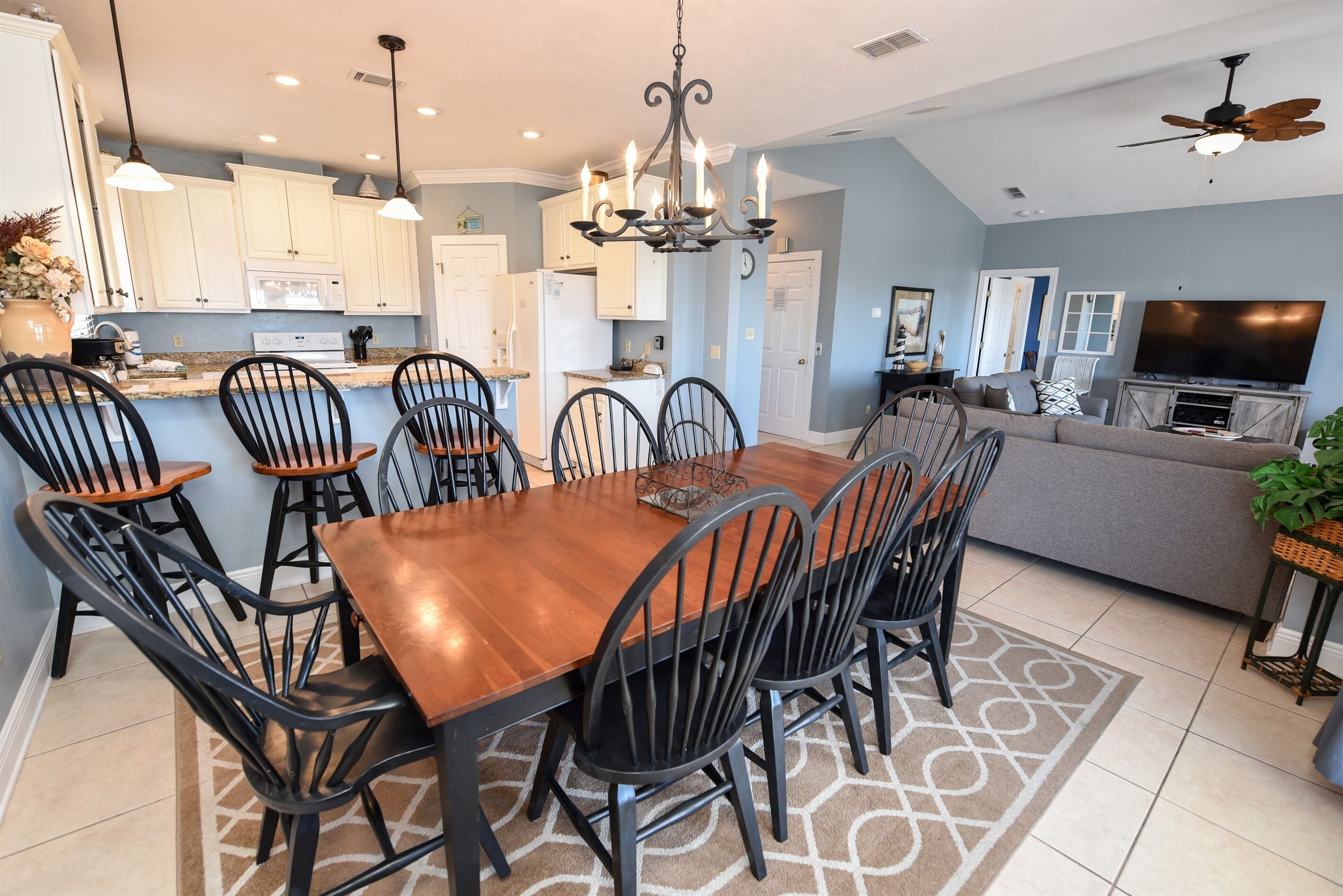 A modern kitchen with white cabinets, a wooden dining table, and black chairs.