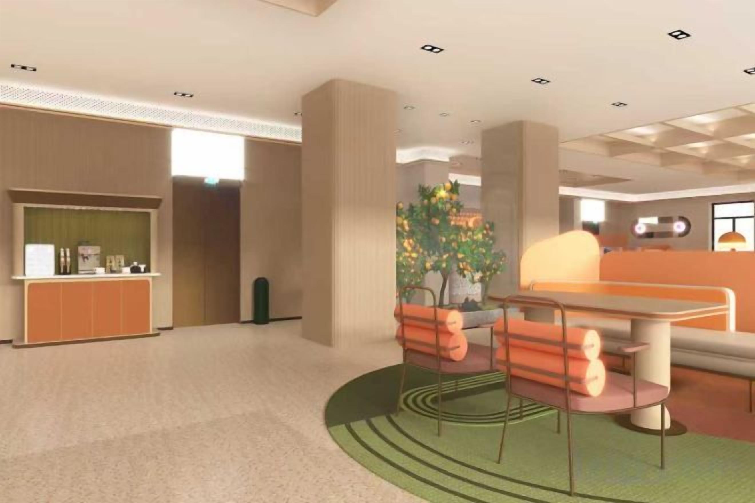 A hotel lobby with a reception desk, seating area, and a large plant.