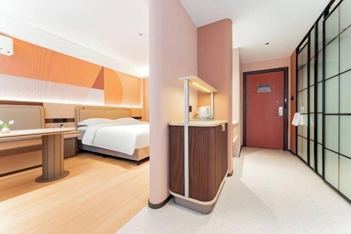 Ein modernes Hotelzimmer mit Bett, Nachttisch und Spiegel.