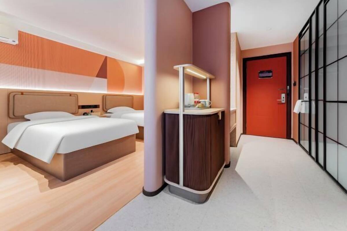 Ein Hotelzimmer mit Bett, Schreibtisch, Stuhl und Kleiderschrank.