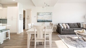 Ein modernes Wohnzimmer mit Essbereich, einem grauen Sofa und einem Gemälde an der Wand.