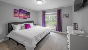 A bedroom with a bed, a window with curtains, a TV mounted on the wall, and artwork on the wall. - Gorgeous 5 Bed/3 Bath, 10 Minutes To Navarre Beach (Navarre)