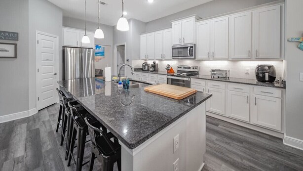 A modern kitchen with white cabinets, stainless steel appliances, and a granite countertop. - Gorgeous 5 Bed/3 Bath, 10 Minutes To Navarre Beach (Navarre)