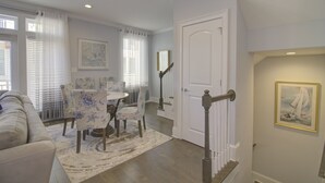 A dining area with a table and chairs, a staircase, and a door leading to another room. - Stunning 2nd Row 3 Bedroom + Loft, 2.5 Bath Townhouse Myrtle Beach North End at Village at 74th (Myrtle Beach)