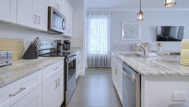 A modern kitchen with white cabinetry, stainless steel appliances, and a marble countertop. - Stunning 2nd Row 3 Bedroom + Loft, 2.5 Bath Townhouse Myrtle Beach North End at Village at 74th (Myrtle Beach)