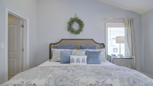 A bedroom with a bed, a nightstand, a lamp, and a window with curtains. - Stunning 2nd Row 3 Bedroom + Loft, 2.5 Bath Townhouse Myrtle Beach North End at Village at 74th (Myrtle Beach)