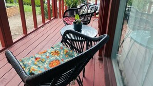 A covered outdoor patio with wooden flooring, black wicker chairs, and a glass table. - Cozy Escape - Beach Community of Playa Del Rey (Los Angeles)