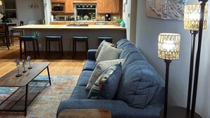 A modern kitchen with wooden cabinets, a central island, and bar stools. - Cozy Escape - Beach Community of Playa Del Rey (Los Angeles)