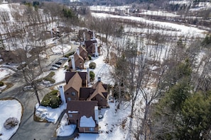 A residential area with houses, a driveway, and snow-covered ground. - Highland Golf Course Views! - Fairway Village 3A (Quechee)