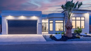 Een modern huis met twee verdiepingen, een garage, grote ramen en een verzorgde tuin.