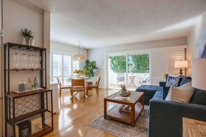 A living room with a sofa, coffee table, and a dining area with chairs and a table. - New lower rates - 1bd condo - walk to everything (La Jolla)