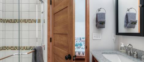 A bathroom with a shower, a sink, and a mirror.
