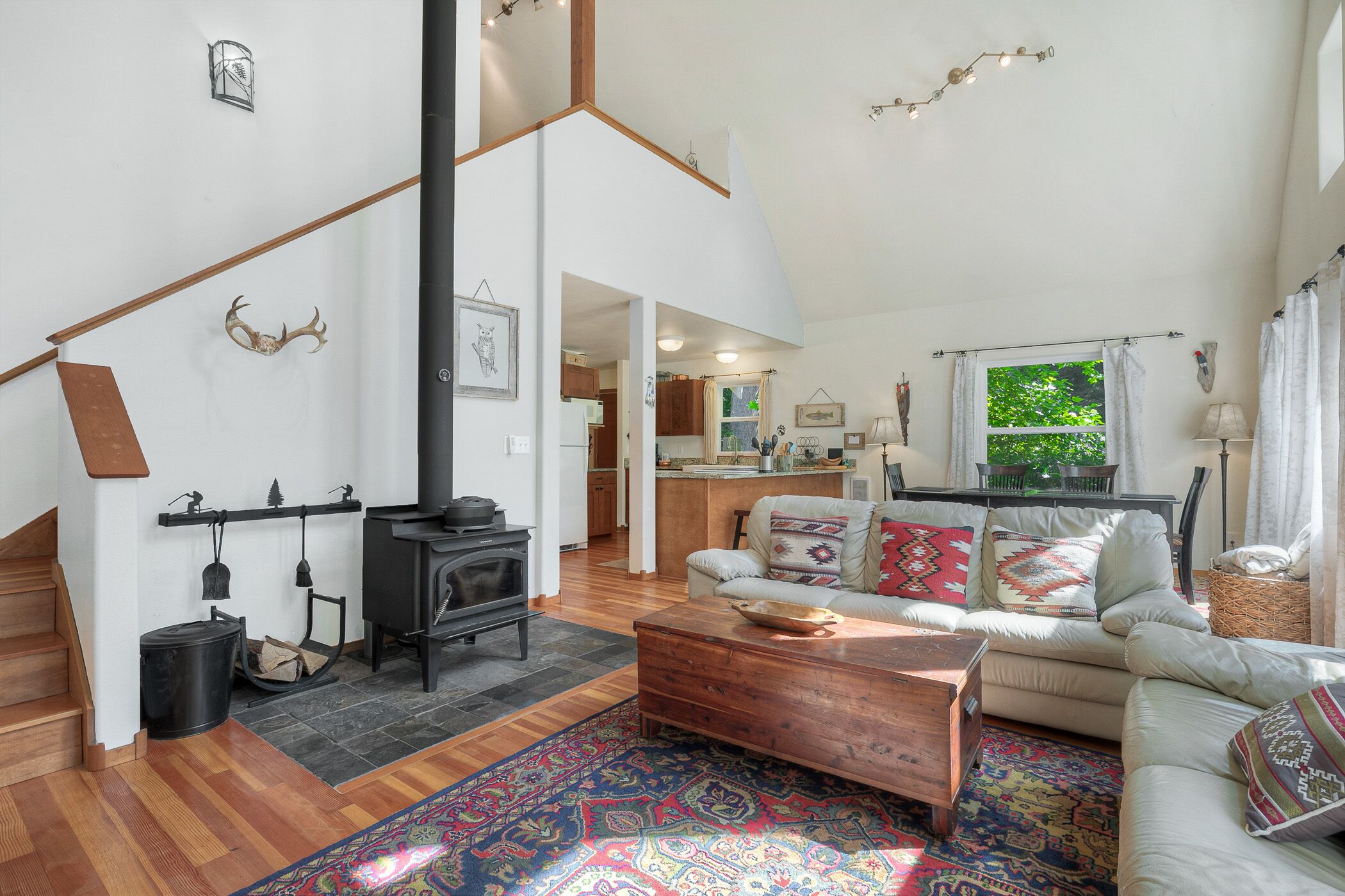 A spacious living room with a fireplace, a sofa set, a coffee table, and a patterned rug.