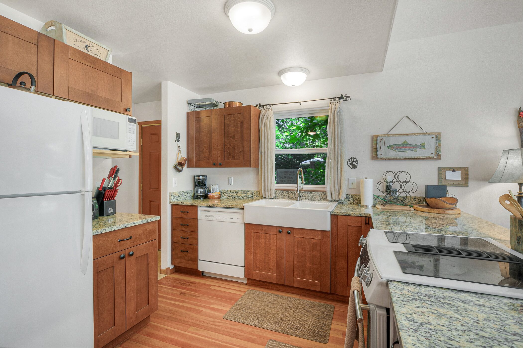 A compact kitchen with wooden cabinets, a white refrigerator, a dishwasher, and a stove.