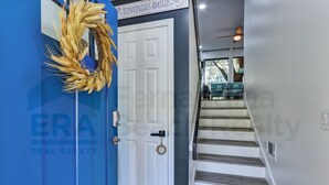 Una puerta azul con un adorno dorado, una puerta blanca con cerradura, y una escalera que lleva a un balcón.