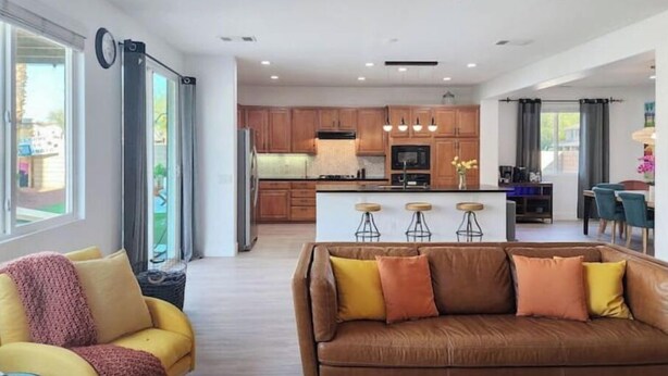 Una sala de estar moderna con un sofá de cuero marrón, un sillón amarillo y una mesa de centro.