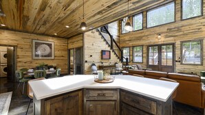 Ein großzügiges Cabin-Interieur mit einer großen Kücheninsel, Holzwänden und einer Treppe, die in eine obere Ebene führt.