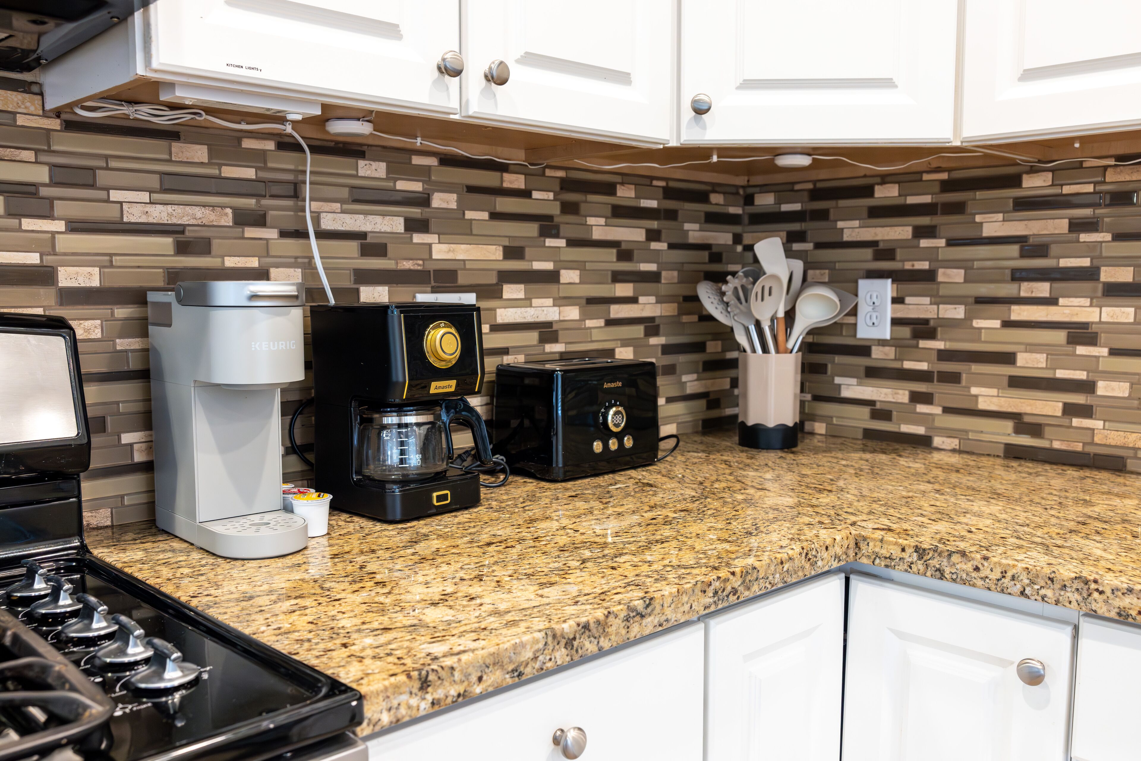 A kitchen with a granite countertop, a coffee maker, a toaster, and a stove.