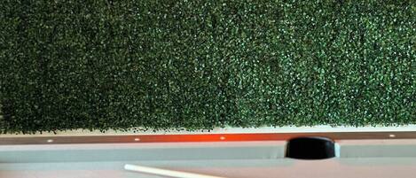 A pool table with balls and a cue stick, a neon sign reading "Scottsdale", and a green textured wall.