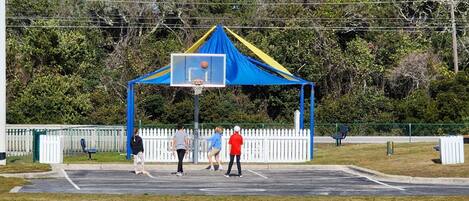 A basketball court with a blue and yellow tent structure.