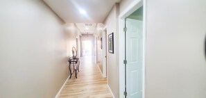 Stylish hallway with a door, table, and chair, featuring framed artwork and a glass-panelled door.