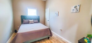 Cozy retreat with a single bed, tufted headboard, and a window with blinds.