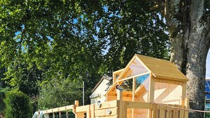 Eine Spielanlage aus Holz mit Rutsche und Kletterelementen.