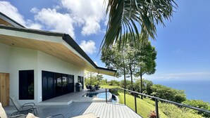 A modern house with a wooden deck, outdoor seating, and a view of the ocean. - Fantastic Ocean View Villa (Dominical)