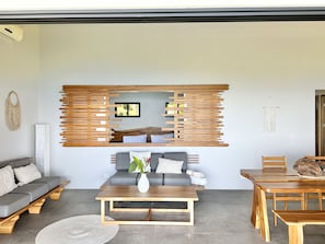 Un salon moderne avec un canapé gris, une table basse en bois et un coin repas doté de meubles en bois.
