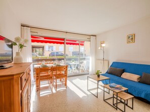 Relax in this stylish living room with a sofa, dining table, and TV, leading to a patio area.