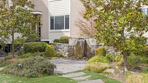 A landscaped garden with a stone wall, a small waterfall, and a paved pathway. - Experiencing Edmonds, In the Heart of it All! (Edmonds)