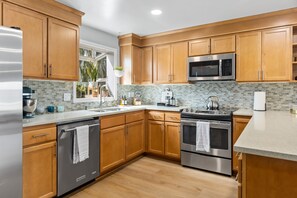 A modern kitchen with wooden cabinets, stainless steel appliances, and a tiled backsplash.