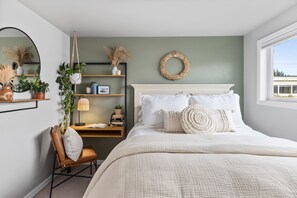 A bedroom with a bed, a chair, a desk, shelves, and a window.