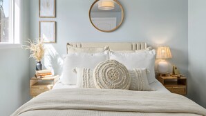 A neatly arranged bedroom with a bed, bedside tables, a mirror, and framed artwork on the wall. - Experiencing Edmonds, In the Heart of it All! (Edmonds)