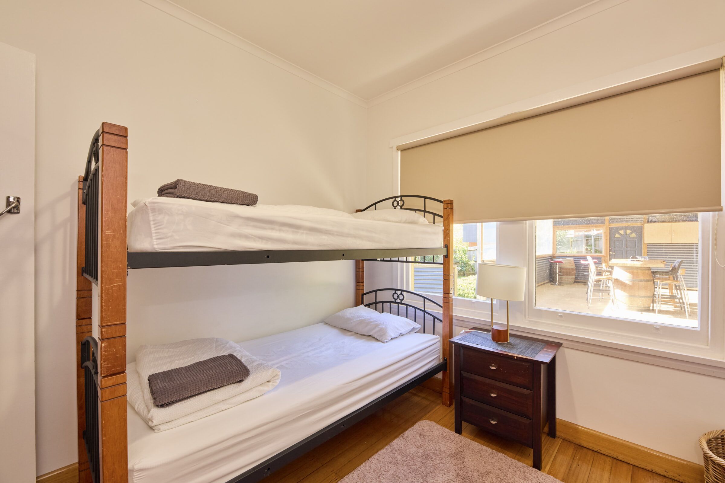 A bunk bed room with a window, a small table, and a lamp.