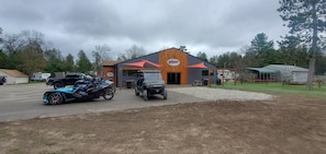 A building with a prominent logo, a gravel driveway, and several vehicles parked in front. - cozy 2 bedroom close to trails and boat launch three minutes (Richfield Township)