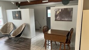 A dining area with a wooden table and chairs, a cushioned chair, and a painting on the wall. - cozy 2 bedroom close to trails and boat launch three minutes (Richfield Township)