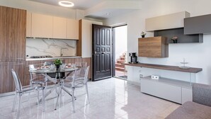 Une cuisine moderne avec un pare-feu en marbre, un coin repas avec des chaises transparentes et un espace café intégré.