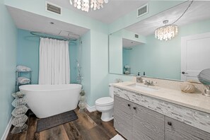Un baño moderno con una bañera independiente, un espejo grande y un tocador con salpicadero de azulejos.