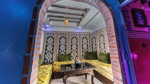 Une pièce au décor traditionnel, comprenant un ensemble de canapés, une table basse et un mur orné d’un motif.