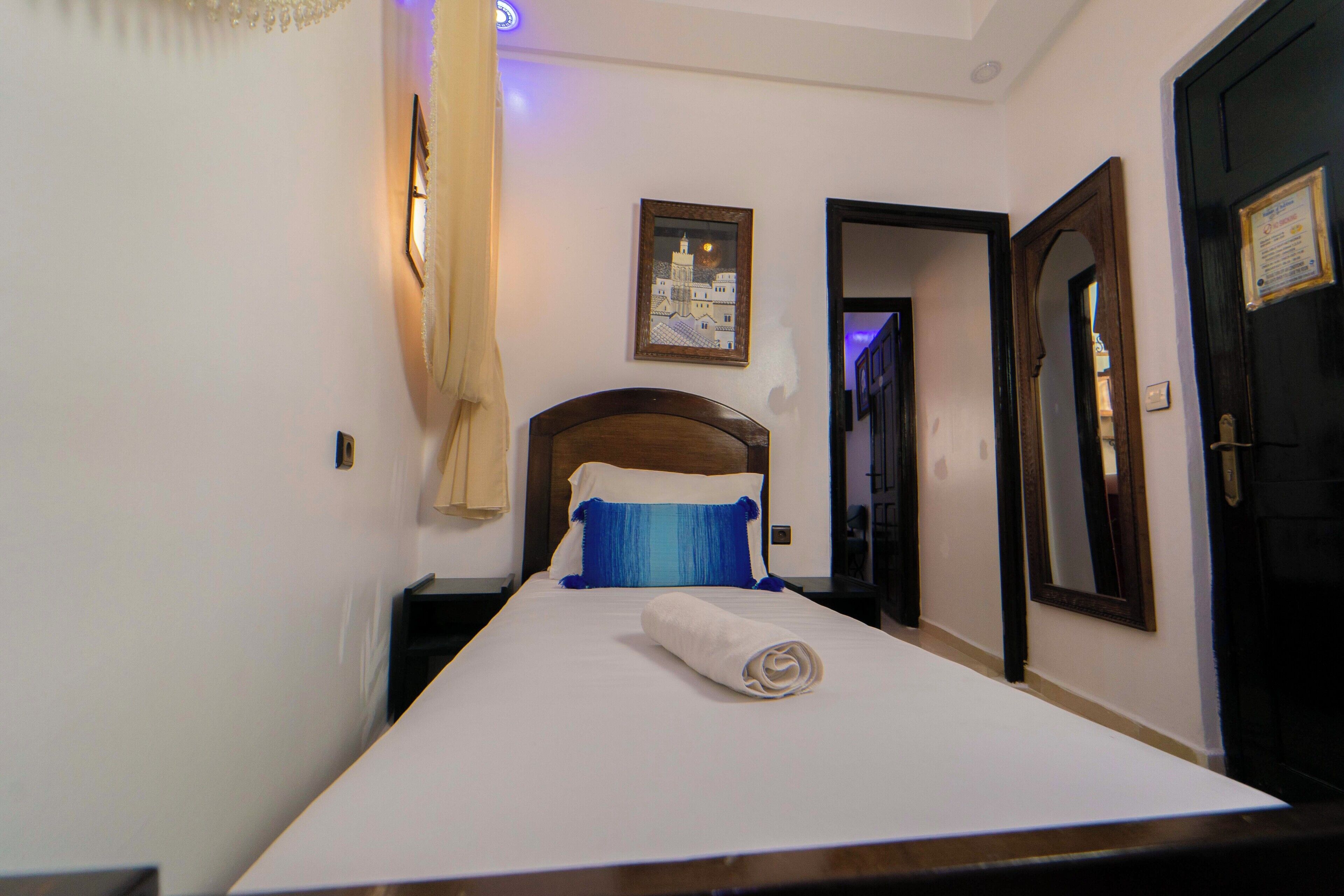A hotel room with a bed, a nightstand, a wall-mounted picture, and a door.