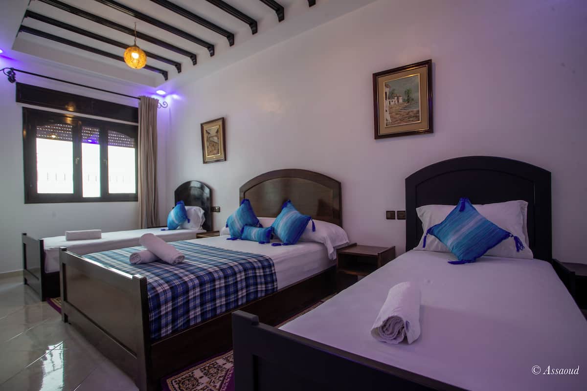 Habitación de hotel con dos camas, un ventanal con cortinas, una lámpara en el techo y un cuadro en la pared.