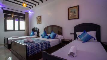 A hotel room with two beds, a large window with curtains, a ceiling light, and a framed picture on the wall.