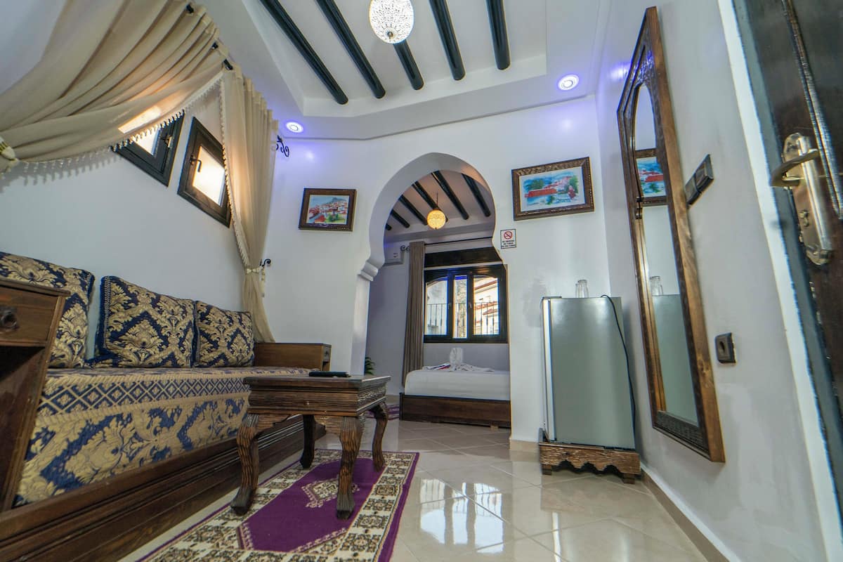 Una habitación con sofá, cama, mesa, espejo y puerta.