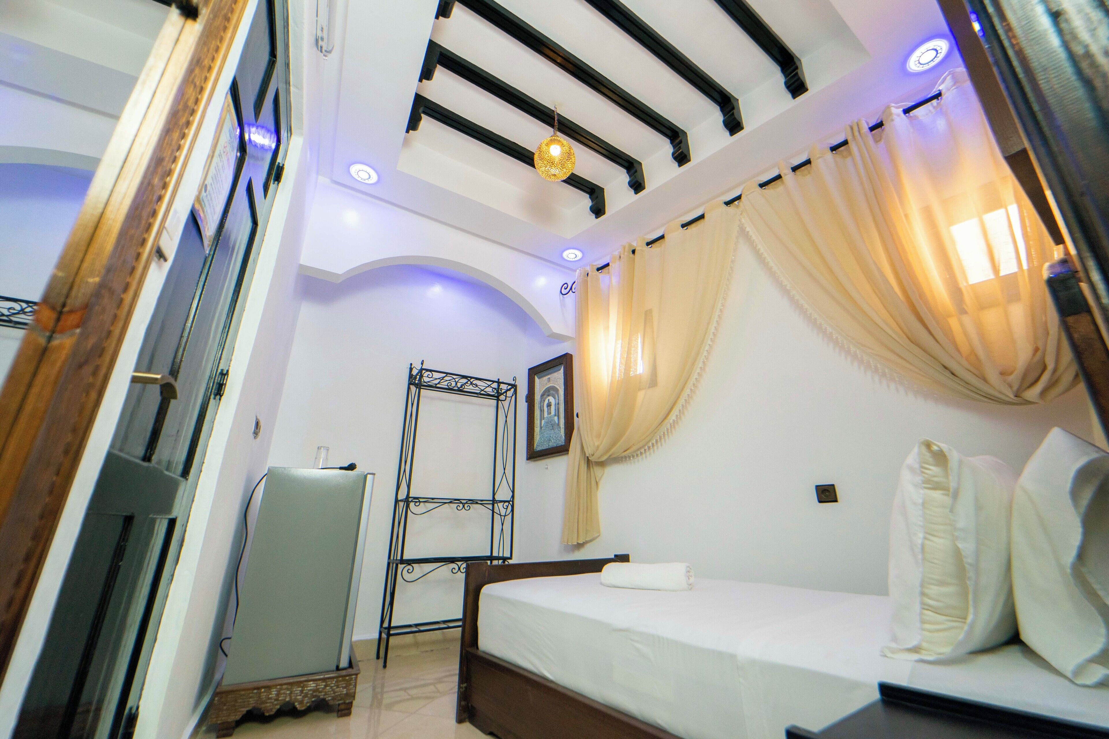 Un dormitorio con cama, armario, espejo e iluminación empotrada en el techo.