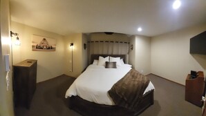 A hotel room with a bed, bedside lamps, a small table, and a wall-mounted picture. - Cozy Mountain Condo (Windham)